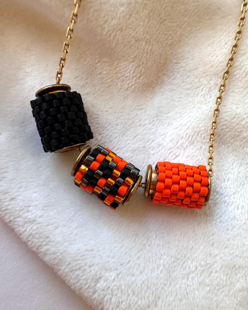 Gold-plated Halloween necklace with three Miyuki beaded charms in black, orange and a black-and-orange pattern with gold-coloured accents, displayed on a jewellery bust – Fleur du Jour