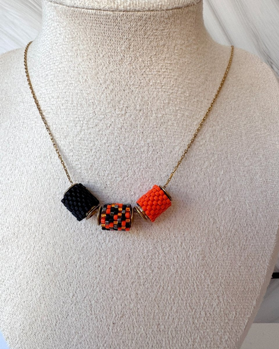 Vergoldete Halloween-Halskette mit drei Miyuki-Perlencharms in Schwarz, Orange und einem schwarz-orangefarbenen Muster mit goldfarbenen Akzenten auf einer Schmuckbüste - Fleur du Jour