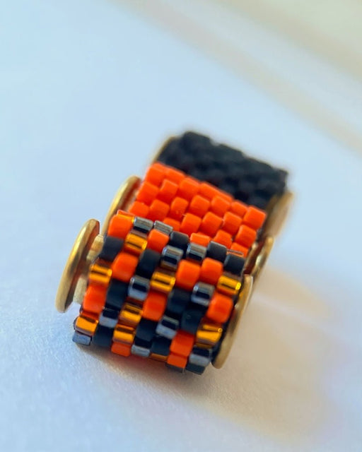 Vergoldete Halloween-Halskette mit drei Miyuki-Perlencharms in Schwarz, Orange und einem schwarz-orangefarbenen Muster mit goldfarbenen Akzenten auf einer Schmuckbüste - Fleur du Jour