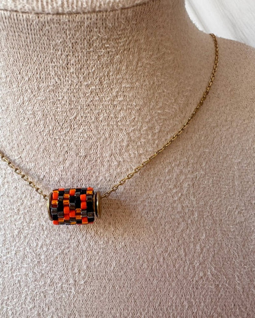 Vergoldete Halloween-Halskette mit drei Miyuki-Perlencharms in Schwarz, Orange und einem schwarz-orangefarbenen Muster mit goldfarbenen Akzenten auf einer Schmuckbüste - Fleur du Jour