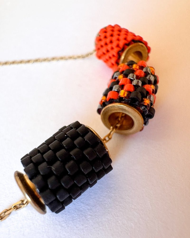 Vergoldete Halloween-Halskette mit drei Miyuki-Perlencharms in Schwarz, Orange und einem schwarz-orangefarbenen Muster mit goldfarbenen Akzenten auf einer Schmuckbüste - Fleur du Jour