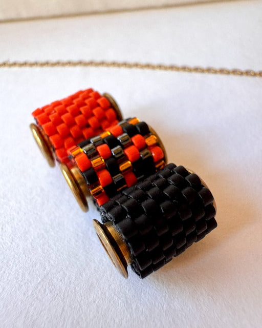 Vergoldete Halloween-Halskette mit drei Miyuki-Perlencharms in Schwarz, Orange und einem schwarz-orangefarbenen Muster mit goldfarbenen Akzenten auf einer Schmuckbüste - Fleur du Jour