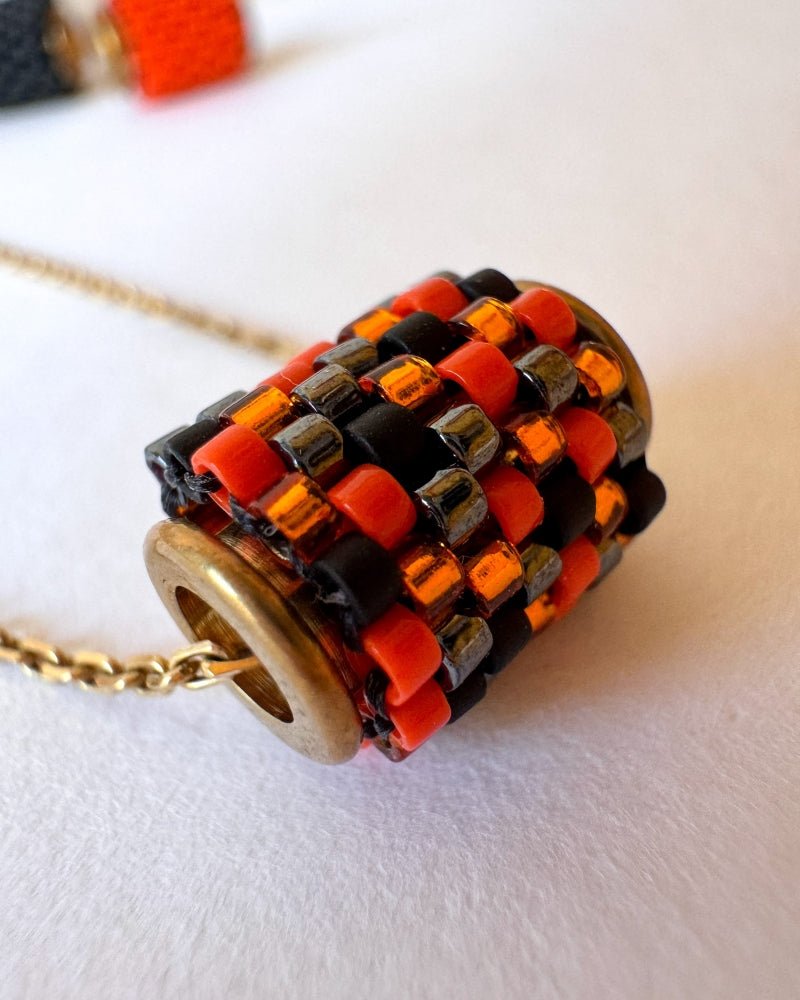 Vergoldete Halloween-Halskette mit drei Miyuki-Perlencharms in Schwarz, Orange und einem schwarz-orangefarbenen Muster mit goldfarbenen Akzenten auf einer Schmuckbüste - Fleur du Jour