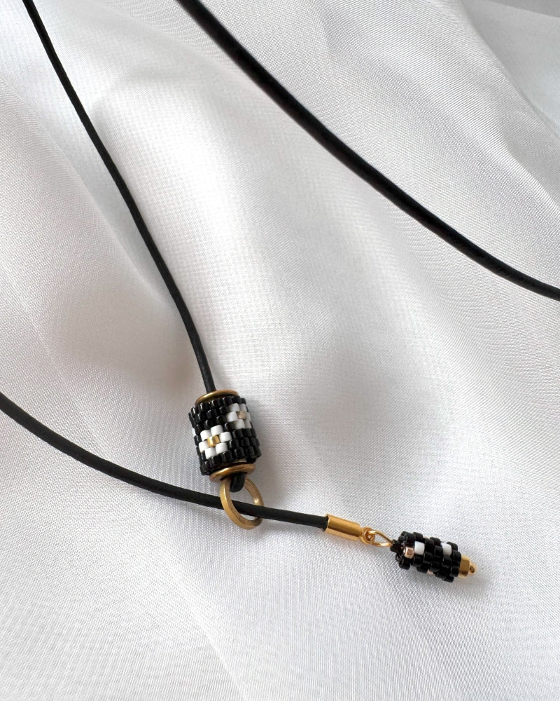 Minimalist black lariat necklace with adjustable length, featuring floral beaded pendant and matching charm - Fleur Du Jour