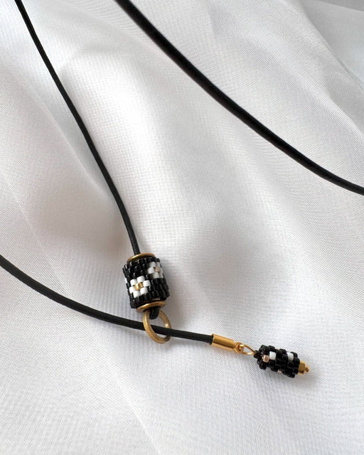 Minimalist black lariat necklace with adjustable length, featuring floral beaded pendant and matching charm - Fleur Du Jour