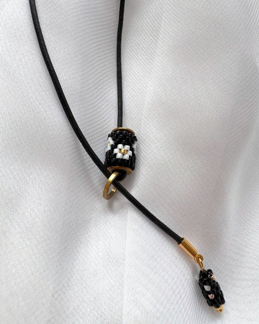 Minimalist black lariat necklace with adjustable length, featuring floral beaded pendant and matching charm - Fleur Du Jour