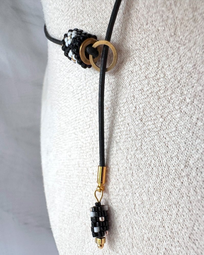 Minimalist black lariat necklace with adjustable length, featuring floral beaded pendant and matching charm - Fleur Du Jour