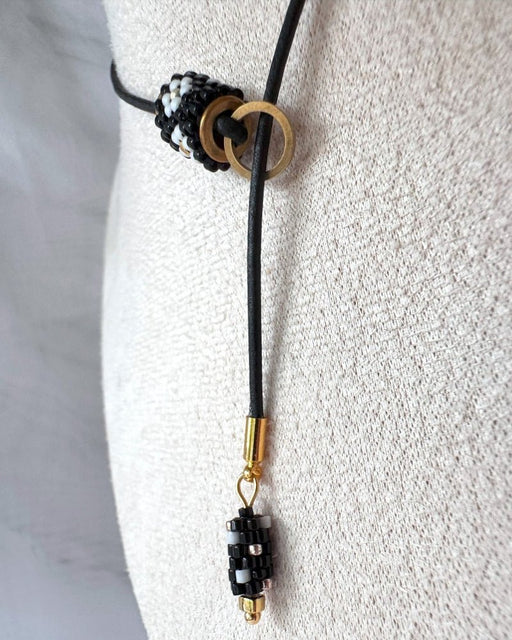 Minimalist black lariat necklace with adjustable length, featuring floral beaded pendant and matching charm - Fleur Du Jour