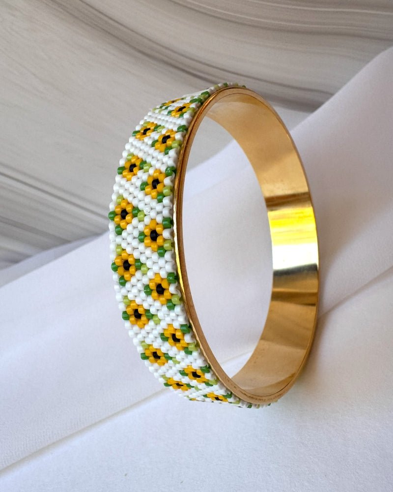 Wide gold-plated sunflower bangle with white Miyuki Delica beadwork, yellow flowers and green leaves