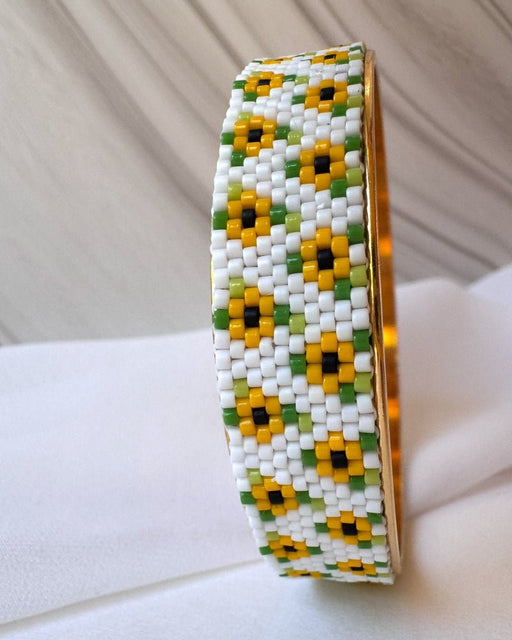 Breiter vergoldeter Sonnenblumen-Armreif mit weißer Miyuki-Delica-Perlenarbeit, gelben Blüten und grünen Blättern